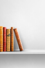Row of old books on white shelf. Vertical background