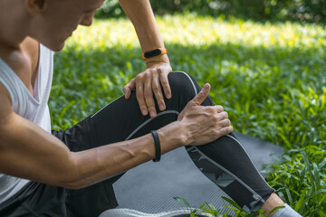 Close-up photo of man touching his knee with his hand. Man injured his knee. Sporty fit active young caucasian man in sportswear sitting 