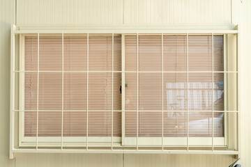 steel windows of the cream-colored house, which is glass and has a cage around the window to protect the house