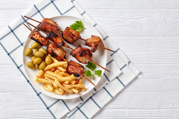 grilled pork kebabs with potato fries on a plate