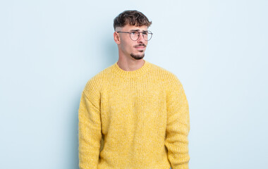 young handsome man looking puzzled and confused, wondering or trying to solve a problem or thinking