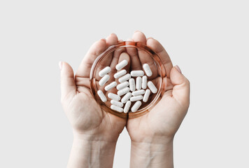 Pills on glass saucer in female hands. Pharmaceutical medicaments.