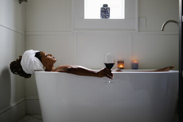 Black Woman taking relaxing bath with glass of wine