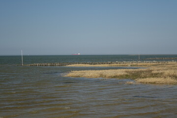 Sahlenburg beach at high tide with big cargo ship in the background on a sunny spring day,...