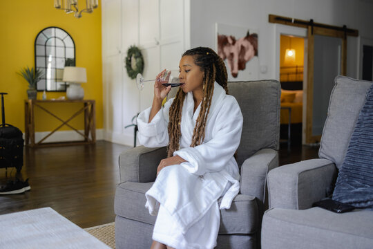 Woman in bathrobe drinking wine in living room
