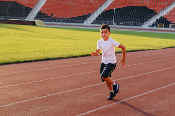 A large group of children, boys and girls, run and play sports at the stadium during sunset. A healthy lifestyle.