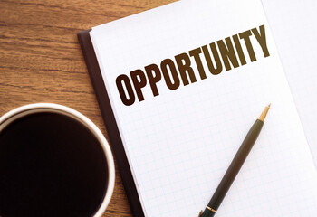 Notebook with text OPPORTUNITY on wooden table with coffee, pencil and glasses