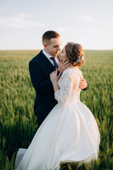 the groom and the bride walk along the wheat green field