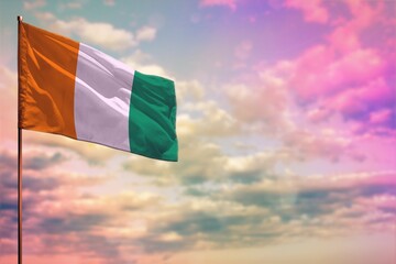 Fluttering Cote d Ivoire flag mockup with the space for your content on colorful cloudy sky background.