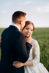 the groom and the bride walk along the wheat green field