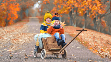 Kinder fahren im Bollerwagen durch die Herbstallee