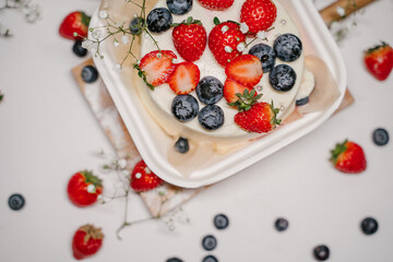 Beautiful white cake decorated with strawberries, blueberries and flowers