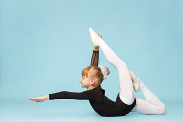 Little gymnast girl with blond hair in a beautiful black leotard. Children's sports, gymnastics