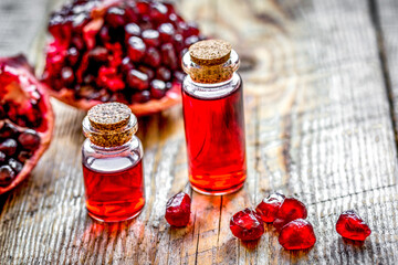 sliced pomegranate and extract in glass on wooden background