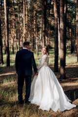 the bride and groom are walking in a pine forest