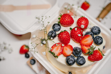 Beautiful white cake decorated with strawberries, blueberries and flowers