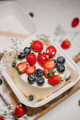 Beautiful white cake decorated with strawberries, blueberries and flowers