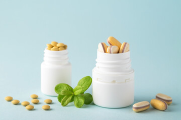 Fototapeta na wymiar Vitamins and herbal supplements in jars with a green plant on a blue background..Biologically active additives. Dietary supplements.