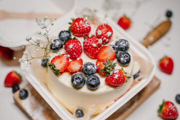 Beautiful white cake decorated with strawberries, blueberries and flowers