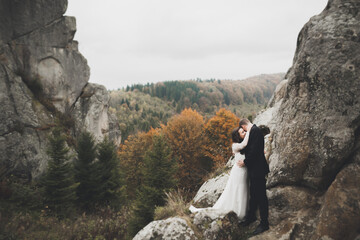 Happy wedding couple posing over beautiful landscape in the mountains