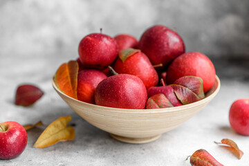 Beautiful fresh red apples with autumn leaves in a wooden vase