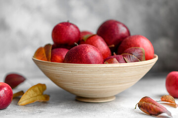 Beautiful fresh red apples with autumn leaves in a wooden vase