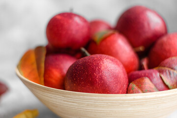 Beautiful fresh red apples with autumn leaves in a wooden vase