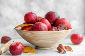 Beautiful fresh red apples with autumn leaves in a wooden vase