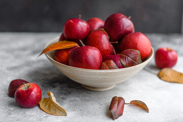 Beautiful fresh red apples with autumn leaves in a wooden vase