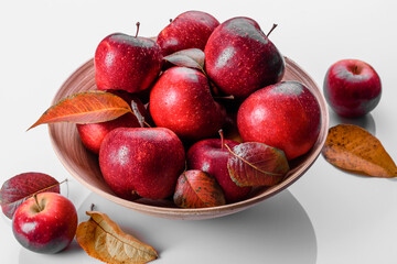 Beautiful fresh red apples with autumn leaves in a wooden vase