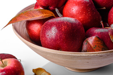 Beautiful fresh red apples with autumn leaves in a wooden vase