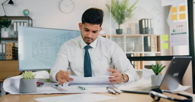 Unhappy angry bearded architect crumpled schemes while working over project in modern design office,problems in work concept