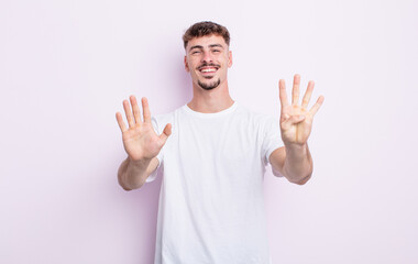young handsome man smiling and looking friendly, showing number nine or ninth with hand forward,...