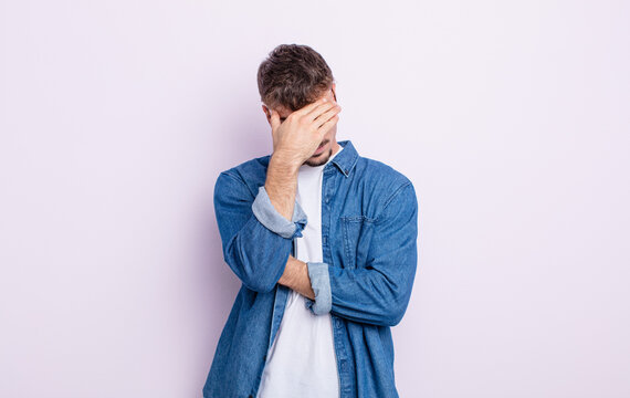 young handsome man looking stressed, ashamed or upset, with a headache, covering face with hand