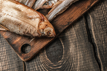 Dried fish on a dark wooden table, beer snacks.