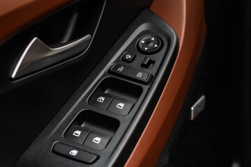 Close up view of button controlling window in modern car interior. Vehicle interior detail. Door handle with windows controls