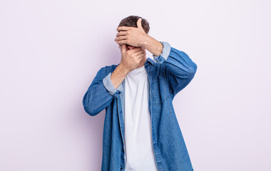 young handsome man covering face with both hands saying no to the camera! refusing pictures or...
