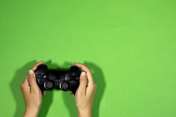 hands holding a black joystick, game controller isolated on green background © hadjanebia