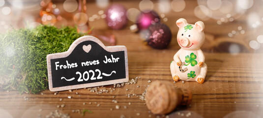 glücksschwein mit kleeblatt und einer kleinen tafel auf der steht frohes neues jahr 2022