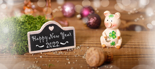 glücksschwein mit kleeblatt und einer kleinen tafel auf der steht happy new year 2022