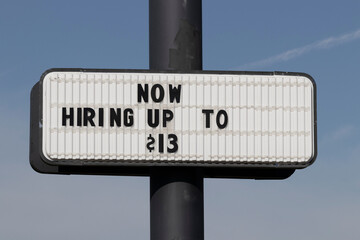 Now Hiring Up to $13 sign. Amid a nationwide shortage of workers, companies, businesses and...