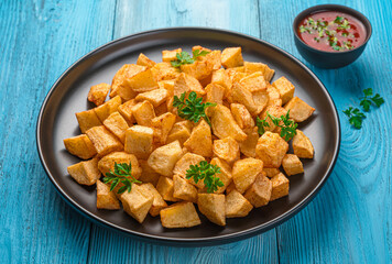 Patatas bravas, Spanish tapas with spicy tomato sauce on a blue background.