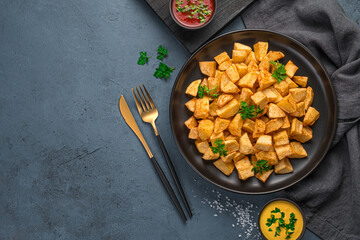 Patatas bravas with sauce on a dark background.