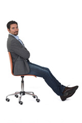 sideview of a man sitting on chair, looking at camera  on white  background