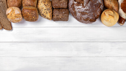 Different types of bread on a white  table ,top view. Bakery products, copy space