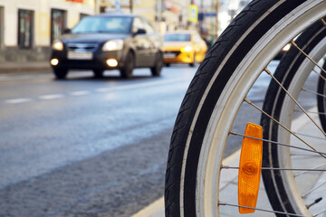 Bicycle wheel against the background of an automobile wheel. The concept of comparing bicycle and road transport..