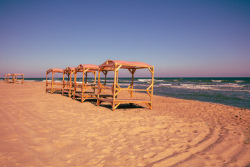 Seascape in the evening. Wooden sun gazebos on the deserted beach