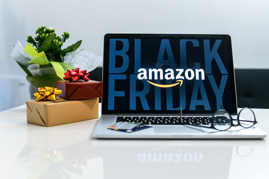 Purchasing Christmas gift in the Amazon online shop the black friday. Logo on the laptop monitor. Purchase of Christmas gifts. E-commerce, tech, shopping online concept. Milan, Italy - November 2021