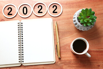 Business concept of top view 2022 goals list with notebook, cup of coffee over wooden desk