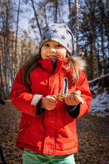 Joyful preschool aged girl in red jacket in deep autumn forest